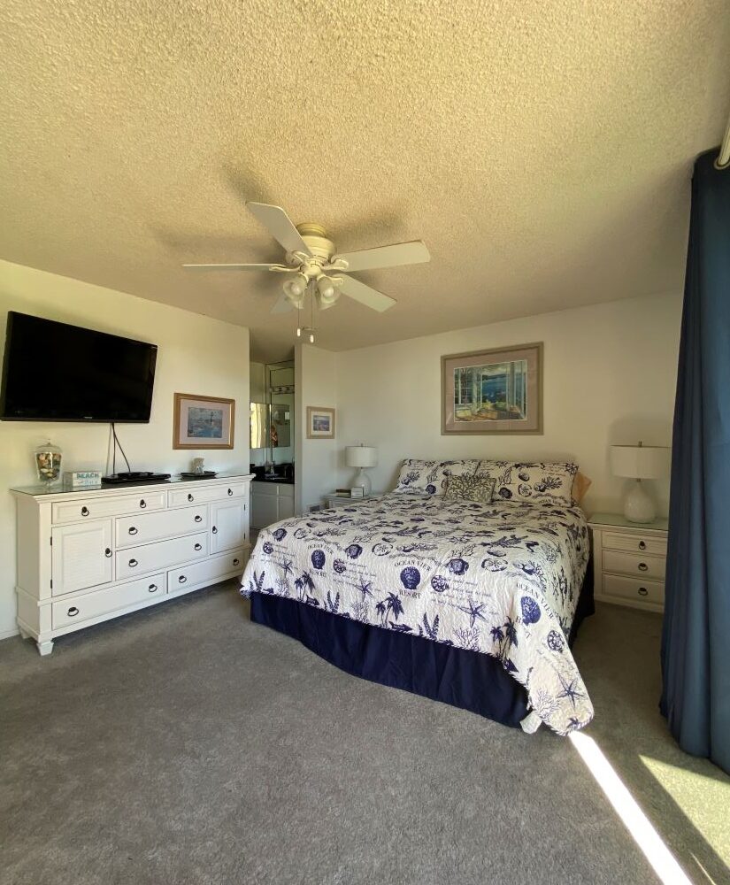 Master Bedroom with white dresser, wall mounted flat screen tv, night tables, with table lamps and ceiling fan